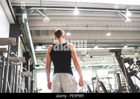 Young man in modern crossfit gym, standing. Rear view. Copy space. Stock Photo