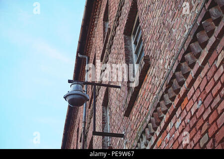 Industrial design lamp on abandoned industrial building. Old factory with red brick wall facade, diagonal from below view Stock Photo