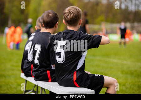 Football soccer game for children. Kids substitute players sitting on a bench. Football sports tournament for young boys Stock Photo