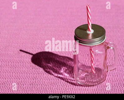Empty vintage mug with a pink straw and lid on pink background Stock Photo