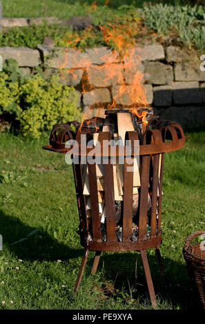 front view of burning old rusty fire basket in the garden Stock Photo