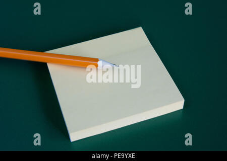 stick note with pencil on green blackboard background. Copyspace. Stock Photo