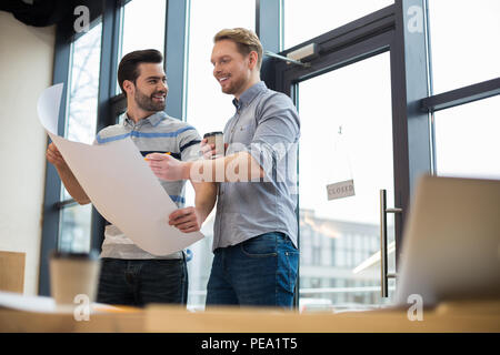 Productive cooperation. Cheerful smart male engineers standing together and discussing their project while working together Stock Photo