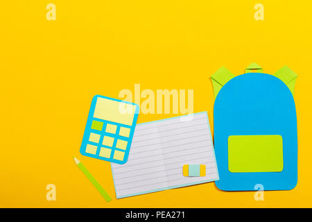 School education papercut background. School bag backpack, notebooks and calculator paper cut on yellow background Stock Photo