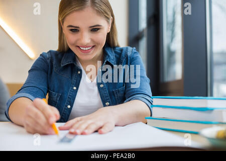 Talented designer. Nice happy positive woman sitting at the table and doing a drawing while working on her project Stock Photo