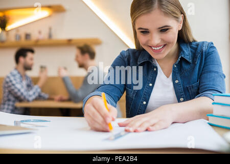 Creative designer. Positive nice creative woman sitting at the table and smiling while doing a drawing Stock Photo