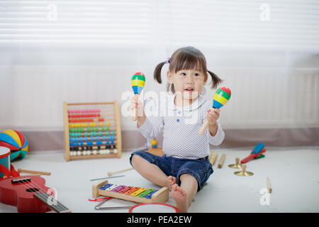 baby girl play maracas at home Stock Photo