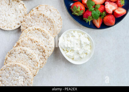 Healthy Snack from Rice Cakes with Ingredients nearby such as Ricotta Cheese and Strawberries on Light Background Stock Photo