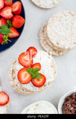 Healthy Snack from Rice Cakes with Ingredients nearby such as Ricotta Cheese, Chocolate Nut Spread and Strawberries on Light Background Stock Photo