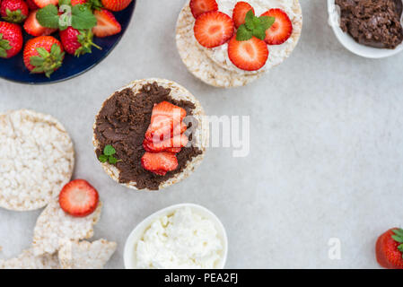 Healthy Snack from Rice Cakes with Ingredients nearby such as Ricotta Cheese, Chocolate Nut Spread and Strawberries on Light Background Stock Photo