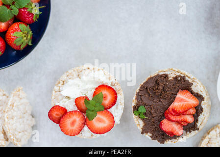 Healthy Snack from Rice Cakes with Ingredients nearby such as Ricotta Cheese, Chocolate Nut Spread and Strawberries on Light Background Stock Photo