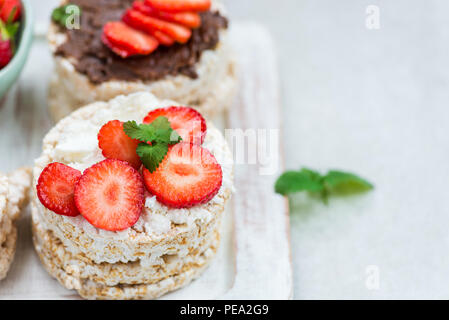 Healthy Snack from Rice Cakes with Ingredients nearby such as Ricotta Cheese, Chocolate Nut Spread and Strawberries on Light Background Stock Photo
