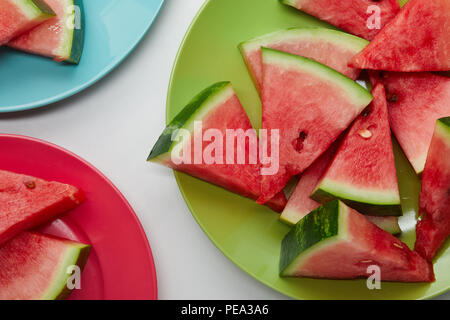 flat lay with watermelon slices on colorful plates on white tabletop Stock Photo