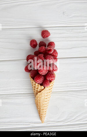 top view of waffle cone with raspberries on wooden table Stock Photo