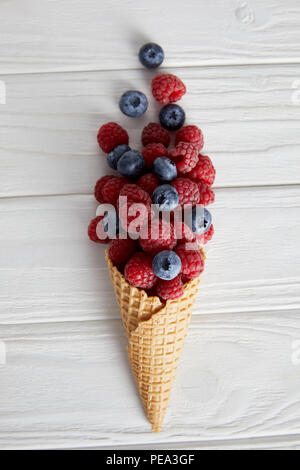 top view of waffle cone with blueberries and raspberries on wooden table Stock Photo