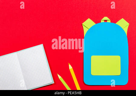 School bag backpack, notebooks and pencils paper cut on red background Stock Photo