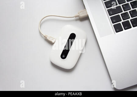 White mobile WiFi device connected to laptop over USB cable Stock Photo