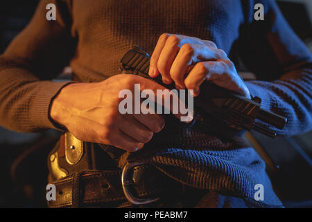 Close-up on a hands of a man carrying a gun with a bullet in the chamber, prepare to use to rob or kill someone. Stock Photo