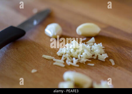 Garlic cloves and chopped garlic on wooden board Stock Photo