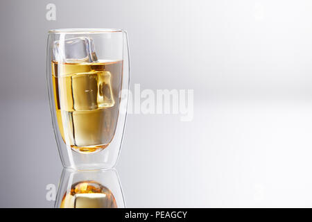 glass of whiskey with ice cubes on reflective surface Stock Photo