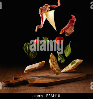 Fresh salad with jamon and cheese for sandwich falling on wooden cutting board Stock Photo