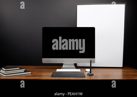 close up view of graphic designer workplace with graphic tablet, blank computer screen, notebooks and empty white board on wooden tabletop Stock Photo
