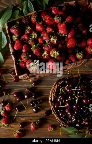 top view of cherries and strawberries in basket and box on wooden surface Stock Photo
