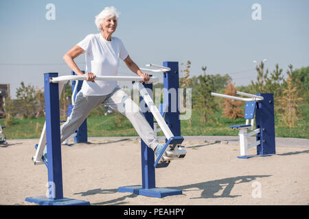 Full length portrait of active senior woman using outdoor exercise machines and enjoying workout, copy space Stock Photo