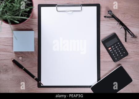 clipboard with blank sheet smartphone and calculator on wooden