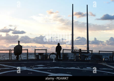 151124-N-FP878-233 MEDITERRANEAN SEA (Nov. 24, 2015) A Sailor stands aft lookout watch aboard USS Carney (DDG 64) as the sun sets over the Mediterranean Sea Nov. 24, 2015. Carney, an Arleigh Burke-class guided-missile destroyer, forward deployed to Rota, Spain, is conducting a routine patrol in the U.S. 6th Fleet area of operations in support of U.S. national security interests in Europe.  (U.S. Navy photo by Mass Communication Specialist 1st Class Theron J. Godbold/Released) Stock Photo