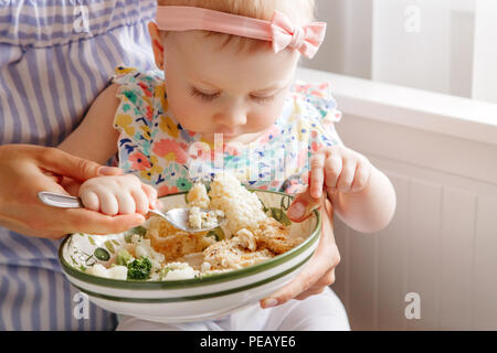 Closeup portrait of young woman mother feeding her girl daughter with vegetables broccoli cauliflower. Healthy organic food for children. Candid lifes