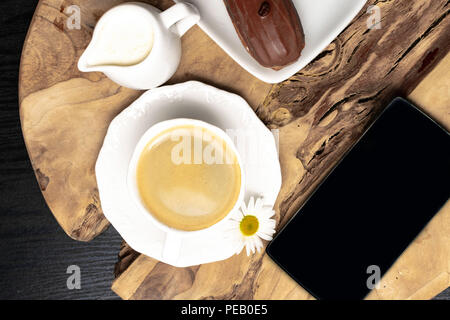 wooden plate with Coffe eclairs with cup of fresh black coffee, pitcher of cream, and coffee beans on Top view. Stock Photo