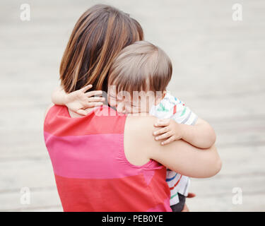 Portrait of  young Caucasian woman mother comforting her crying little toddler boy son outside in park on summer day, parenthood lifestyle concept Stock Photo