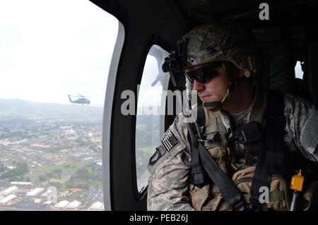Sgt. 1st Class William Henderson, platoon sergeant, 1st Platoon Company B, 2nd Battalion, 35th Infantry Regiment, 3rd Brigade Combat Team, 25th Infantry Division, looks down at Wheeler Army Airfield, Hawaii, as he flies aboard Dec. 2, 2015. Henderson flew from Wheeler to Marine Corps Training Area Bellows to conduct air assault operations. (Photo by Staff Sgt. Armando R. Limon, 3rd Brigade Combat Team, 25th Infantry Division) Stock Photo