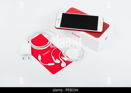 BURGAS, BULGARIA - AUGUST 11, 2018: Apple iPhone 7 Plus Red Special Edition on white background, front view. Charger, earpods and adapter. Stock Photo