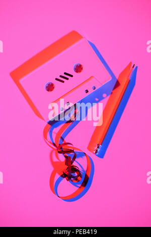 toned pink picture of retro audio cassette with pencil and tape Stock Photo