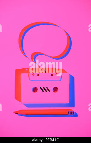 toned pink picture of pencil and retro audio cassette with speech bubble Stock Photo