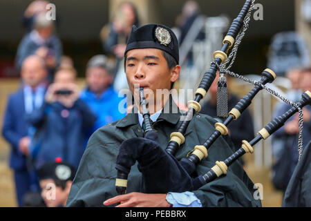 Glasgow, UK. 14th Aug 2018. Rain didn't stop play for the Brisbane Boys College Pipe Band from Australia who entertained the public by playing in rain showers in Buchanan Street, Glasgow. The World Pipe Band Championships are on Saturday 18 August with Pipe bands from around the world competing for the title. Jun Oh from Brisbane is one of their pipers. Credit: Findlay/Alamy Live News Stock Photo