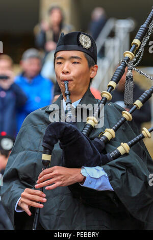 Glasgow, UK. 14th Aug 2018. Rain didn't stop play for the Brisbane Boys College Pipe Band from Australia who entertained the public by playing in rain showers in Buchanan Street, Glasgow. The World Pipe Band Championships are on Saturday 18 August with Pipe bands from around the world competing for the title. JunOh from Brisbane is one of their pipers Credit: Findlay/Alamy Live News Stock Photo
