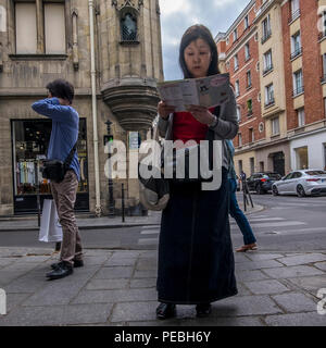 asian girl using ipad to navigate around paris, france Stock Photo