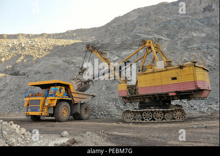 Loading of iron ore on very big dump-body truck Stock Photo