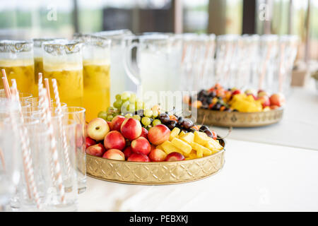 Fresh Fruit platter buffet at business or wedding event venue. Self service or all you can eat - cherries, nectarine, grapes and pineapple. Table with cold drink and snacks and tableware Stock Photo