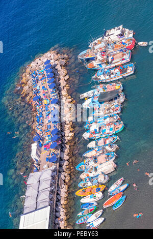 Looking down on a pier in the Marina Grande area of Sorrento in Italy, with the colourful boats tethered in the bay and locals enjoy the sun and sea. Stock Photo