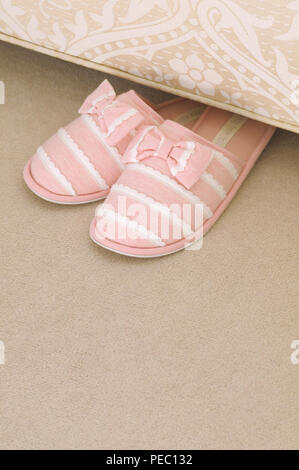 Pink ladies slippers under a divan bed Stock Photo