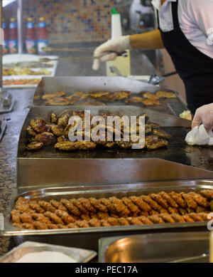 Man fries meat and burger cutlets on a steaming grill Stock Photo
