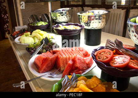 Open buffet at hotel. Sliced watermelon, oranges, tomatoes, grapes in white bowls Stock Photo