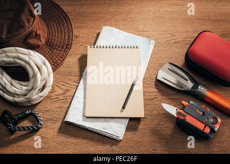 top view of blank notebook with pencil, map and travel items on wooden table Stock Photo