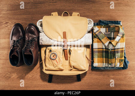 top view of backpack with compass, map and clothes on wooden table Stock Photo