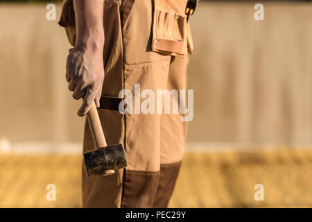 cropped image of construction worker in uniform holding hammer Stock Photo