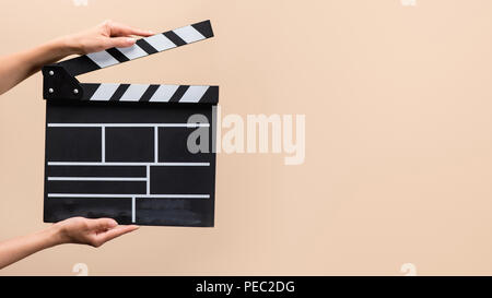 partial view of woman holding clapper board in hands isolated on beige Stock Photo